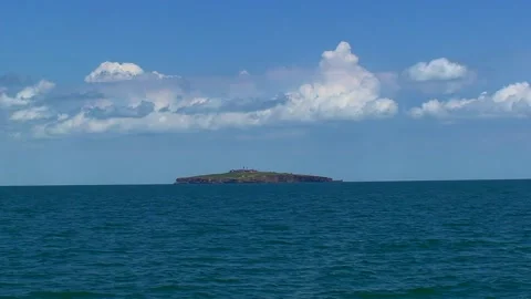 The camera moves slowly along the Snake Island on the horizon, light clouds in Video stock 227489656