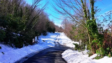 The camera moves slowly, cinematically, along a snowy asphalt road Stock Footage 334789107