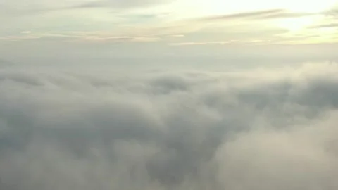 The camera moves slowly over thick clouds to the horizon with the rising sun. Stock Footage 144625716