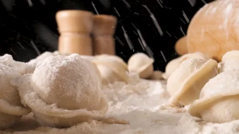 The camera moves slowly through the dumplings and flour. Flour is poured on top. Stock Footage 144907179