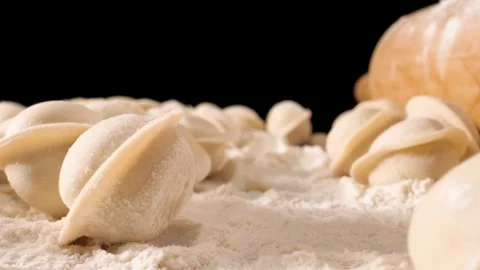 The camera moves slowly through the dumplings and flour. Close-up shot . Black b Stock Footage 144907220