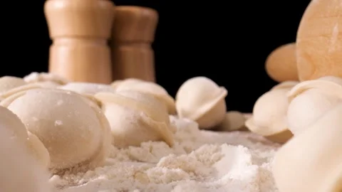 The camera moves slowly through the dumplings and flour. Close-up shot . Black b Видео 144907225