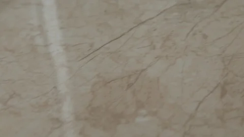 The camera moves smoothly along a beige-colored ceramic floor tile with natural  Stock Footage 106002989