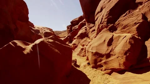 Camera moves through narrow sunlit red rock slot canyon Stock Footage 329559625