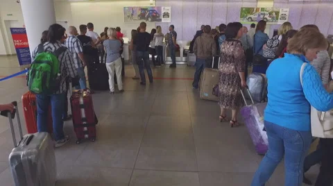 Camera moves through passengers to serviceman at airport check-in desk Stock Footage 57396935