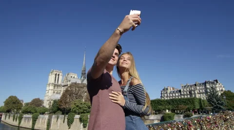 Camera moves through shot as a young couple take a selfie infront of Natre Dame Stock Footage 63028630