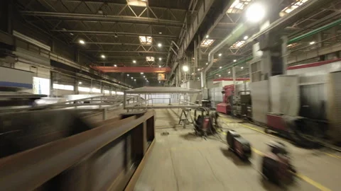 Camera moves through steel frameworks revealing bustling workshop Vídeo Stock 304414822