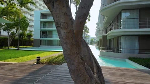 The camera moves through the trees, a modern hotel building with a swimming Stock Footage 276339301
