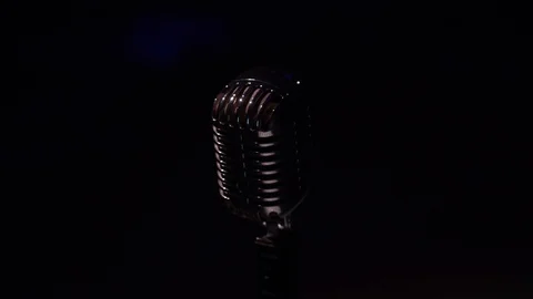 Camera moves up. White spotlights shine on chrome retro mic on black background. Stock Footage 118529139