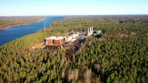 Camera moving above river and showing modern waste recycling plant in autumn Stock Footage 289048961