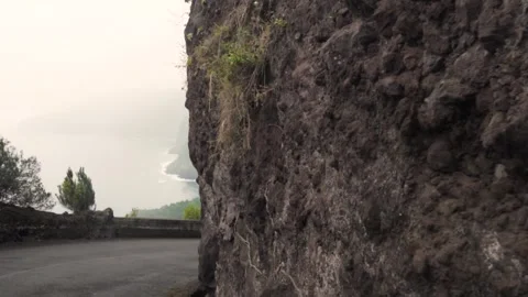 Camera moving along winding mountain road overlooking misty coastline Stock Footage 293158905