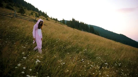 Camera moving around a beautiful young woman in pink dragon pajamas walking on Stock Footage 124541553