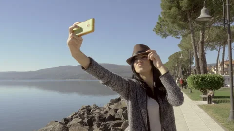 Camera moving around cute young woman with hat taking selfie with cell phone Stock Footage 59863309