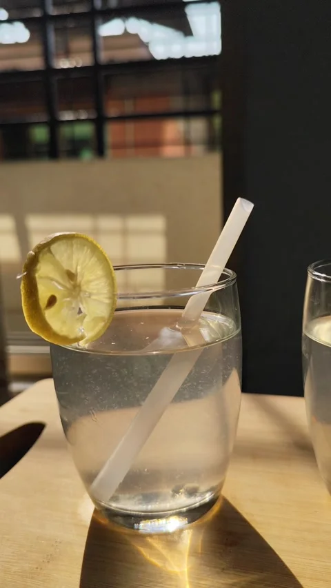 Camera Moving Around Lemon Water Glass with Straw Refreshing Summer Drink. Stock Footage 330397556