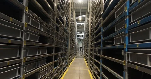Camera is moving back between almost empty iron shelves in the warehouse of the Stock Footage 87389063