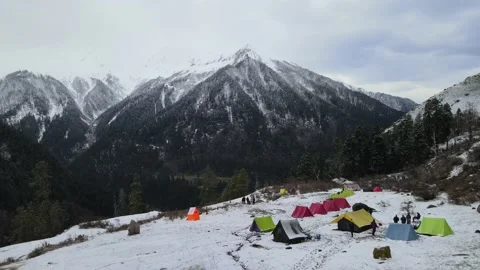 Camera moving back. colorful camping tents. huge snow covered rocky mountain Stock Footage 157664823