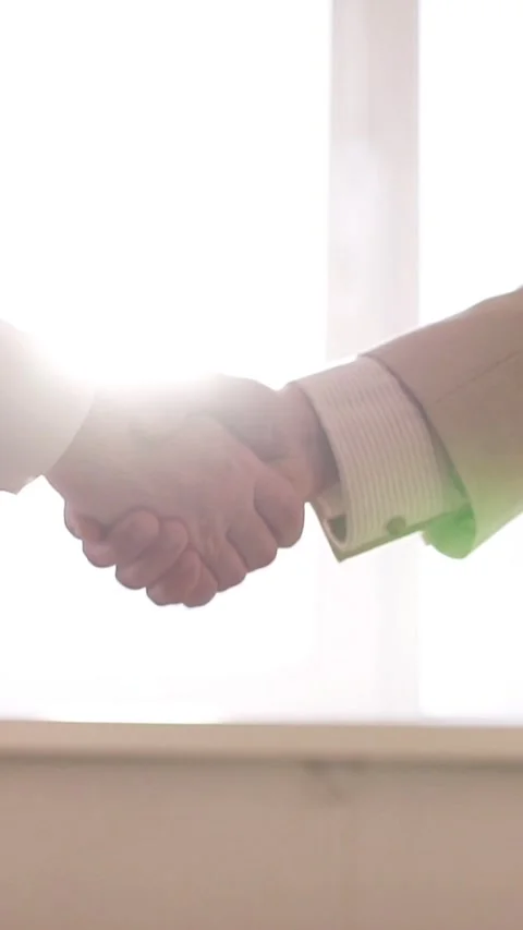 Camera moving during a business handshake with a cinematic lens flare against a Vídeos de archivo 348734898
