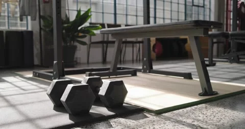 Camera is moving forward and refocusing to highlight three hex dumbbells on Stock Footage 338338322