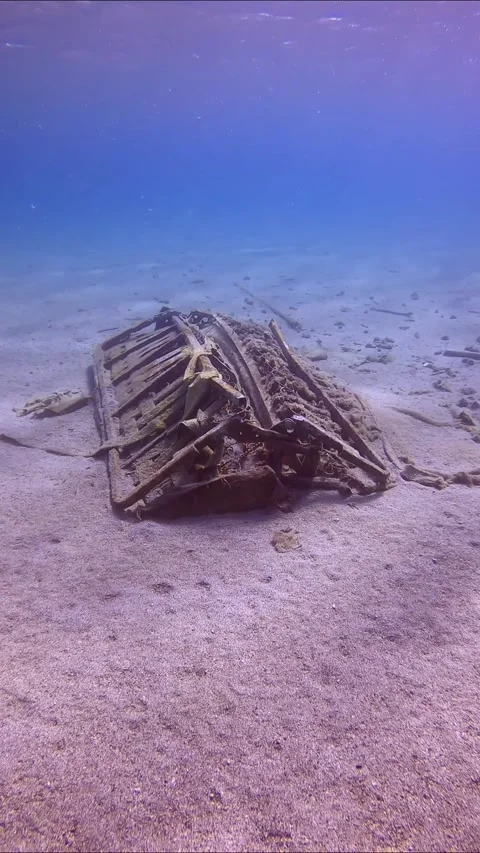 Camera moving forwards approaching to discarded old sofa lying on sandy seabed Stock Footage 255110183