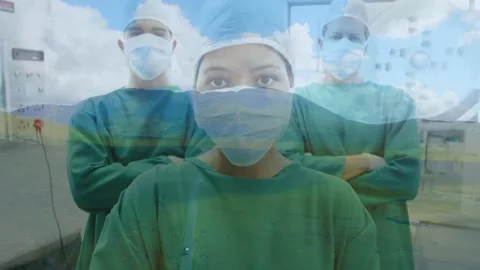 Camera moving up lead doc stepping forward team in green gowns clouds layering Video stock 333968019