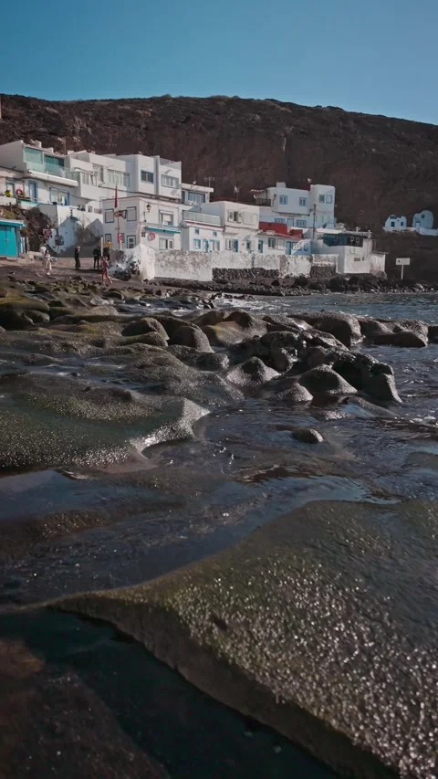 Camera moving left showing volcanic beach with tourists Video stock 294278562