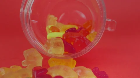 Camera moving out of sweet candy jar. Gummy bears in jar on blue background Stock Footage 139308380