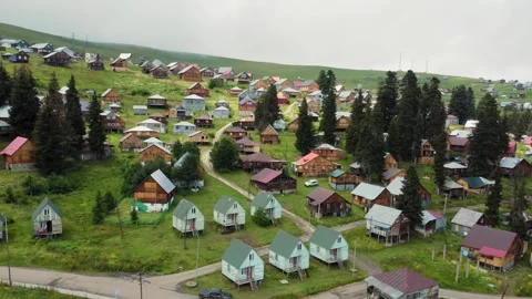 Camera moving over green valley showing wooden houses 스톡 동영상 292805083