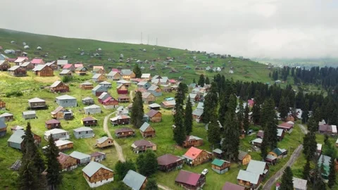 Camera moving over green valley showing wooden houses Stock Footage 292805542