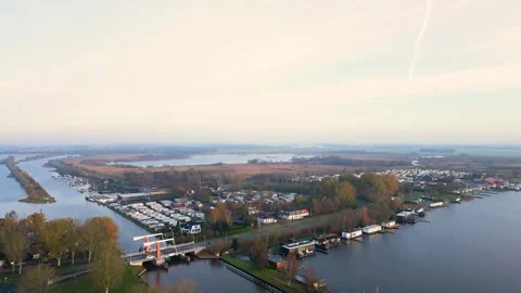 Camera moving over river and revealing village with houses and boats Stock Footage 293158034