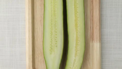 Camera moving over sliced fresh cucumber halves on wooden tray Stock Footage 348308225