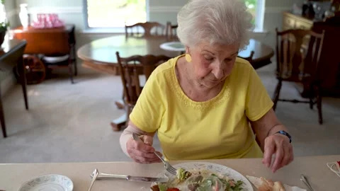 Camera moving to right showing elderly senior woman in dining room eating with a Stock Footage 136425728