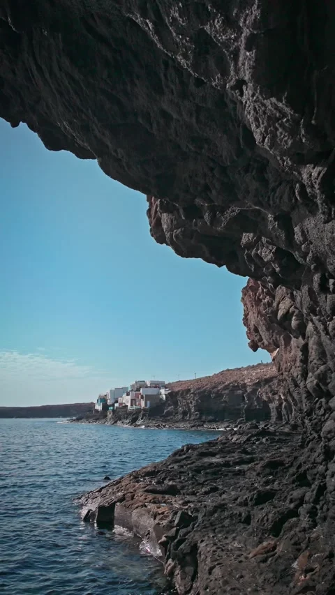 Camera moving through a rocky arch showing volcanic harbor entrance Stock Footage 294278625