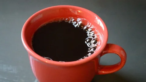 Camera moving through scene until a red cup full of black coffee - horizontal Stock Footage 114995106