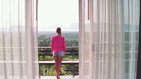Camera moving throught curtian at the villa. Woman standing on terrace and Video stock 100993235