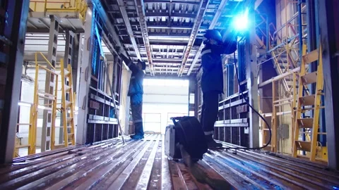 Camera is moving towards the factory labors in protective suits and safety masks Stock Footage 202049090