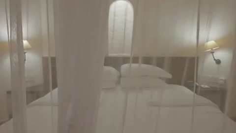 Camera moving towards hotel bed in suite with mosquito net or canopy over it Video stock 307717564