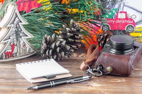 A camera, notebook, pen, and Christmas decorations on a wooden table Foto stock