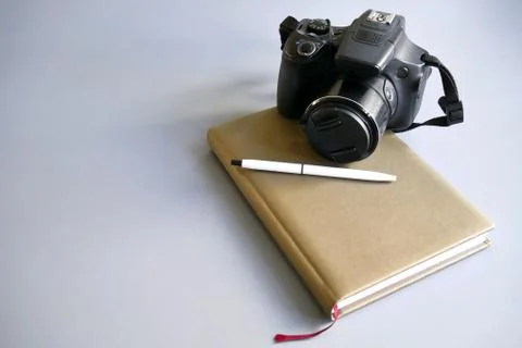 A camera with a notepad and a gray-backed pen Stock Photos