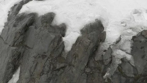 The camera observes a close-up of a snow-covered rock. Rough gray stones in a Stock Footage 148383521