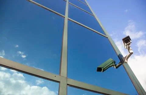Camera on office building reflecting clouds and sky Stock Photos