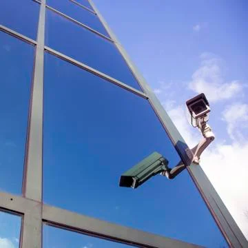 Camera on office building reflecting clouds and sky Stock Photos