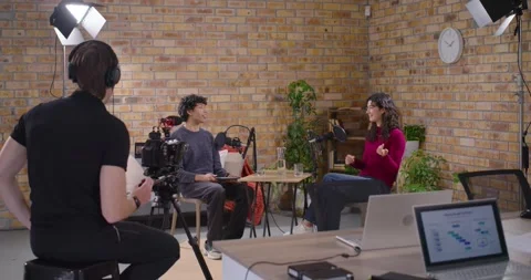 Camera operator rolling, Diverse hosts talking in studio for interview, guest Stock Footage 347459907