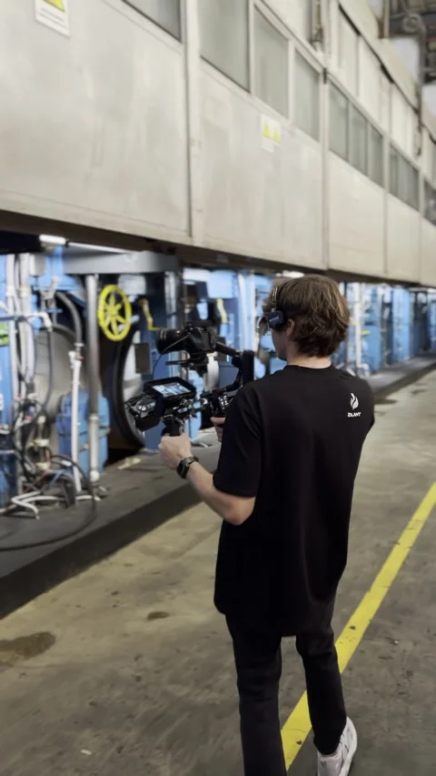Camera operator with tripod moves along industrial aisle Stock Footage 313865917