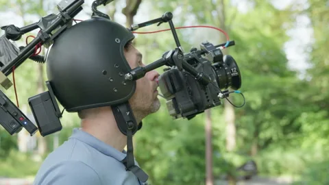 Camera Operator uses Helmet Rig during outdoor Commercial Client Shoot Video stock 336580973