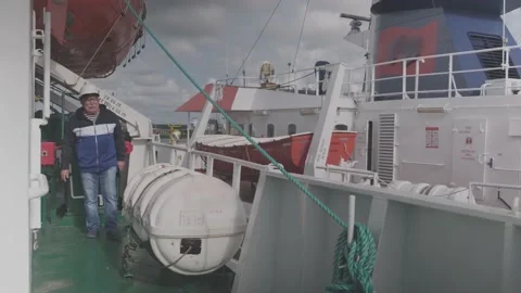 Camera operator walks along green freight vessel deck Stock Footage 148389285