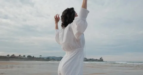 Camera orbits from face to back, smiling woman opens arms to ocean Stock Footage 318592863