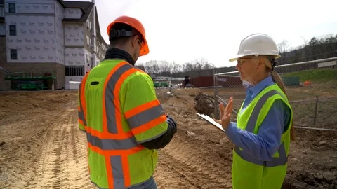 Camera orbits to right and then follows woman engineer and construction foreman Stock Footage 127123777