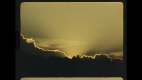 Camera pan across golden sunset clouds over trees on super 8 film Video stock 337799286