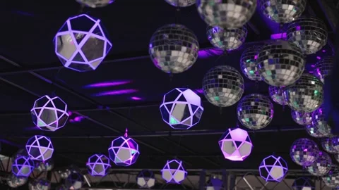 Camera pan down over disco balls and geometric LED lights on truss ceiling in Stock Footage 334115072