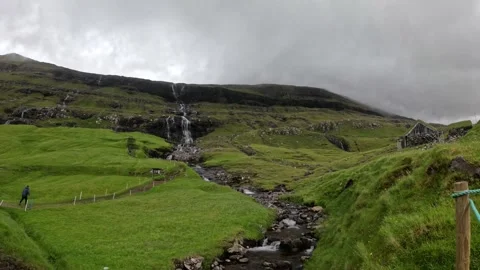 Camera pan over a rocky creek and traditional turf hut under dramatic clouds Stock-Footage 339383268